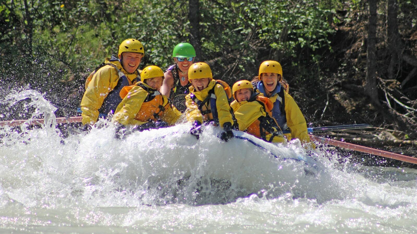 Whitewater rafters in a white raft enjoy the Kicking Horse River whitewater.